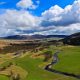 river with fields in the foreground and hills