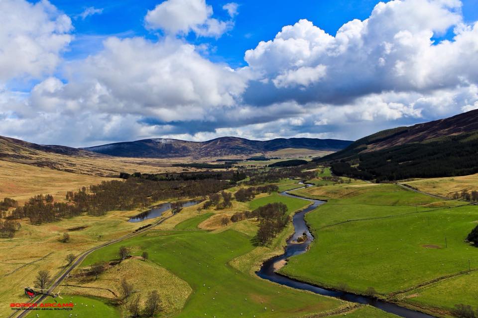 river with fields in the foreground and hills